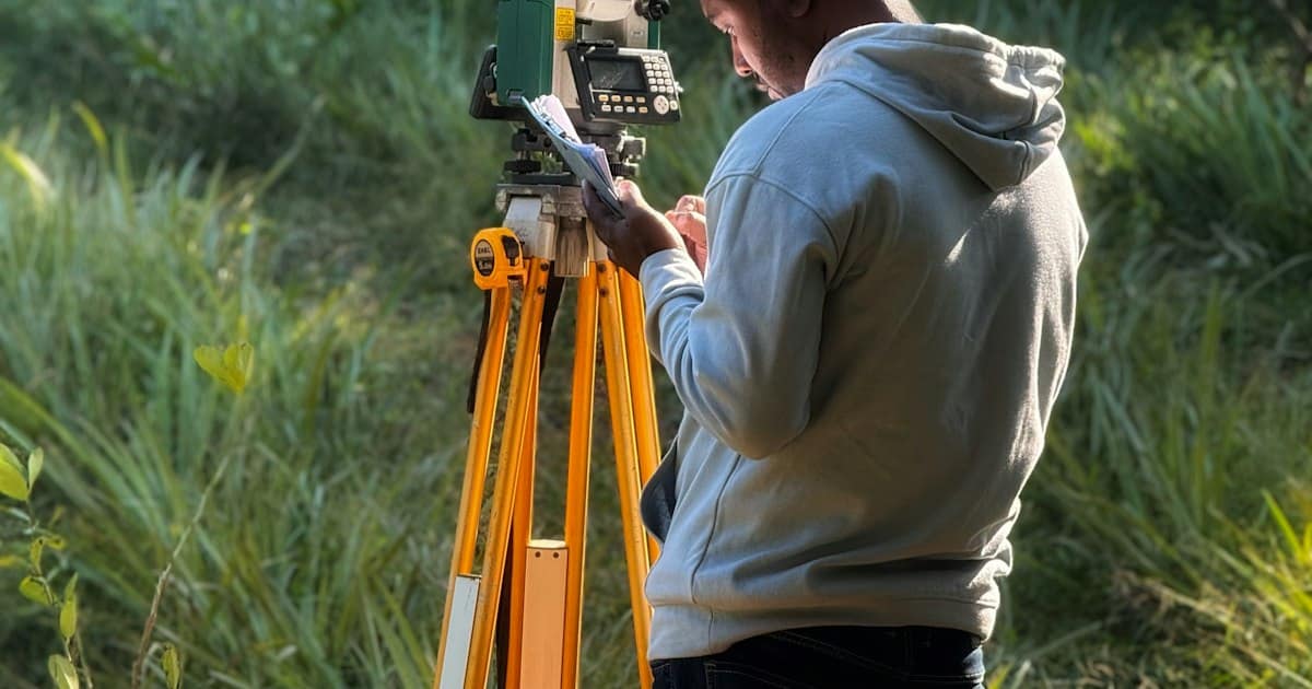 Topógrafo usando una estación total en un campo de pasto