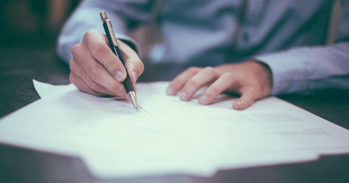 Dos personas revisando y firmando un documento de contrato en una mesa